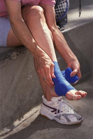 Elderly woman wrapping her sprained ankle after an injury playing raquetball at a gym in Los Angeles, California.